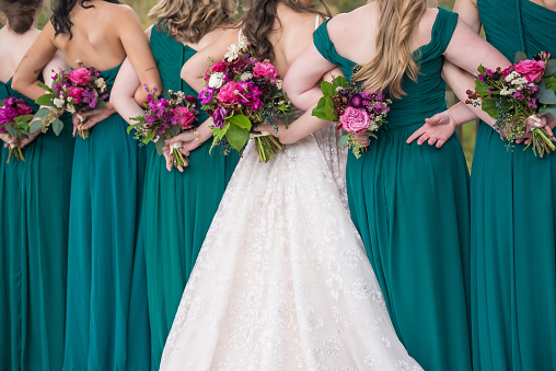 A back view of the bride and bridesmaids holding the bouquets of roses