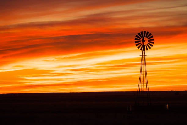 istock Silhouette of a windmill against an orange sunset sky 1459289691
