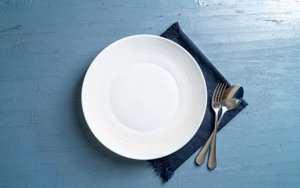 istock Top view of a plate with a fork and a spoon on a blue wooden table 1459290535