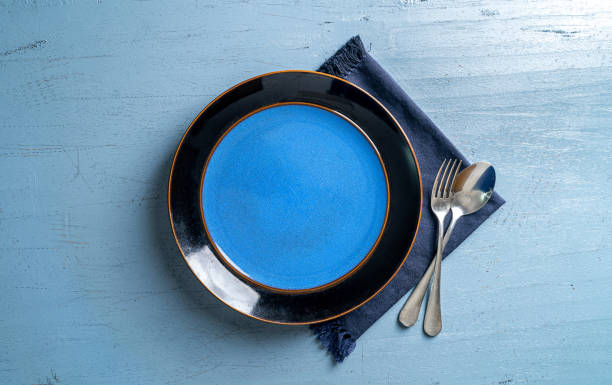 istock Top view of a plate with a fork and a spoon on a blue wooden table 1459290563