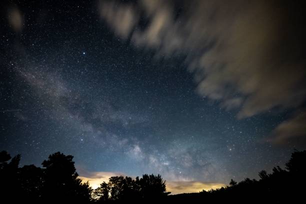istock Night Milky Way view with tree silhouettes and cloudy sky at dawn 1459301854