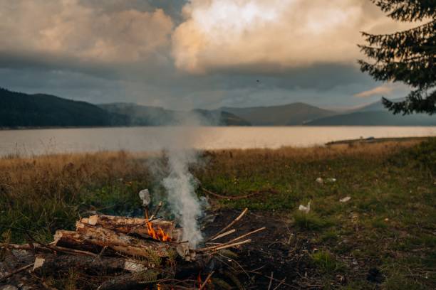 istock Small campfire with gentle flames beside a lake during a glowing sunset 1459304372