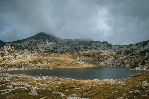 A lake surrounded by hills under a cloudy sky