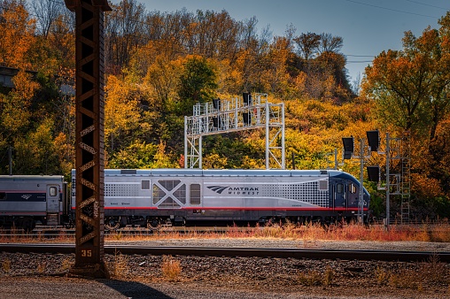 Kansas City, United States – October 22, 2022: An Amtrak train driving against the scenic fall forest in Kansas City, US