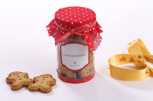 A closeup shot of a jar filled with Christmas Gingerbread biscuits covered with a red cloth