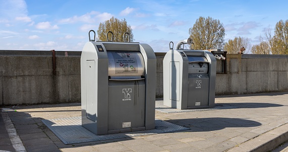 Three multicolored garbage bins for recycling, dumpsters in a row, forest background, copy space available. Galicia, Spain.