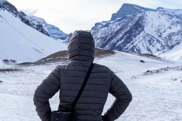 istock Man is standing and looking at the mountains covered by snow. 1459309196