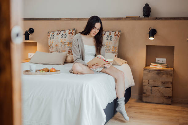 istock Serene woman reading book on soft bed 1459314203