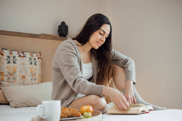 istock Serene woman reading book on soft bed 1459314270