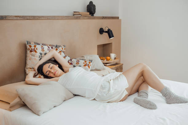 istock Serene woman stretching arms after good sleep on bed 1459314445