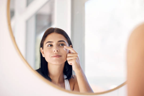 Mirror reflection of woman with skincare cream, spa lotion or dermatology ointment for melasma or acne treatment. Bathroom facial routine, healthcare and face of girl apply cosmetics beauty product stock photo