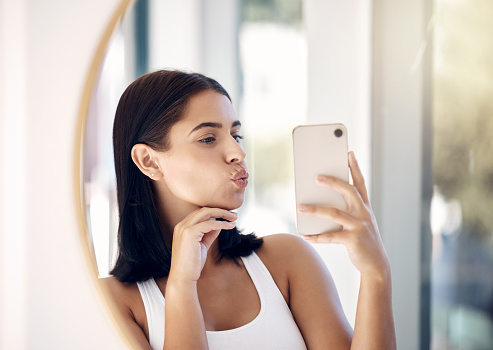 Selfie, phone and woman with mirror in bathroom for beauty, skincare and social media. Hygiene, self care and cleaning with girl and pout in reflection the morning for technology, mobile and internet