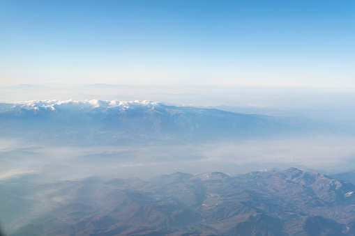 Snowcapped mountains from airplane window. Aerial view.