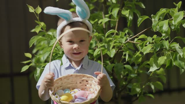 funny kid boy easter bunny ears holding basket full of colorful easter eggs
