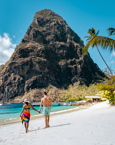 St Lucia , couple walking on the beach during summer vacation on a sunny day at Sugar beach, men and woman on vacation at the tropical Island of Saint Lucia Caribbean Island with a view at the Pitons