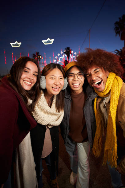 istock Vertical four happy friends taking smiling selfie looking camera standing together at night outdoor. 1459316870