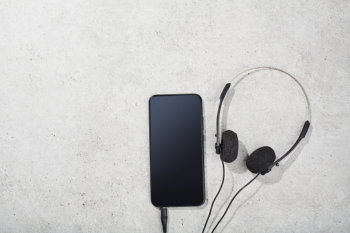 Smart phone and vintage headphones on concrete background. Summer and music