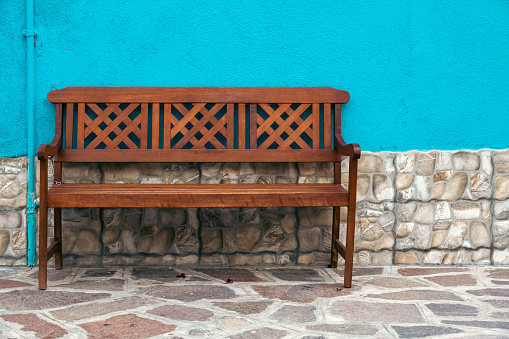 Single wooden bench in front of a turquoise wall