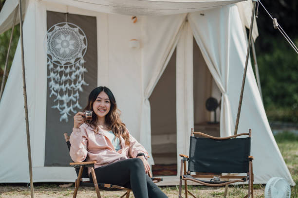 istock Young Asian female sits relaxing outside at a tent. Looking at camera 1459325113