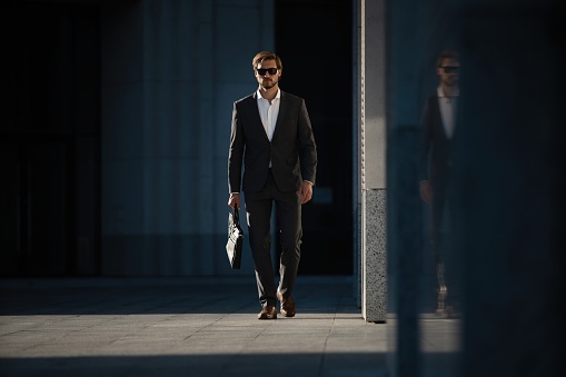 Elegant handsome man in classic suit standing near the office building