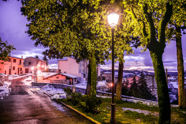 A suggestive winter atmosphere at twilight among the snowy alleys of a medieval village in Umbria in Italy A winter atmosphere in the evening in the snowy alleys of the medieval village of Gualdo Tadino in Umbria, central Italy. The Umbria region, considered the green lung of Italy for its wooded mountains, is characterized by a perfect integration between nature and the presence of man, in a context of environmental sustainability and healthy life. In addition to its immense artistic and historical heritage, Umbria is famous for its food and wine production and for the high quality of the olive oil produced in these lands. Image in high definition format. gualdo tadino stock pictures, royalty-free photos & images