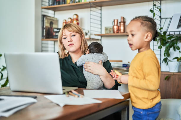 Single mother with kids and working at home Single mother carrying newborn baby and working at home. Woman using laptop while son playing in living room. working at home with children stock pictures, royalty-free photos & images