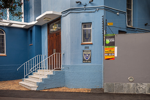 Cape Town, South Africa - December 9th 2022: Stairs and door to a synagogue with posters for security companies