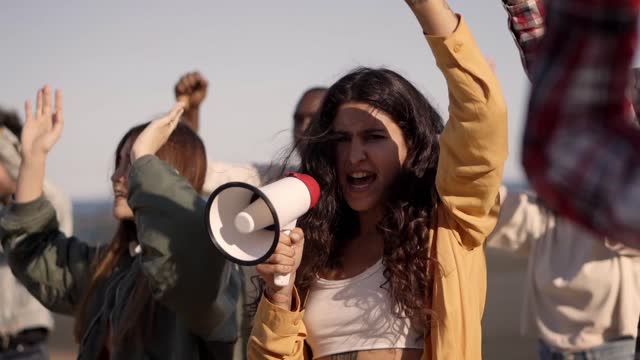 Woman Shouting on Megaphone in a Public Demonstration on the Street. Group of Multiethnic People making Protest.