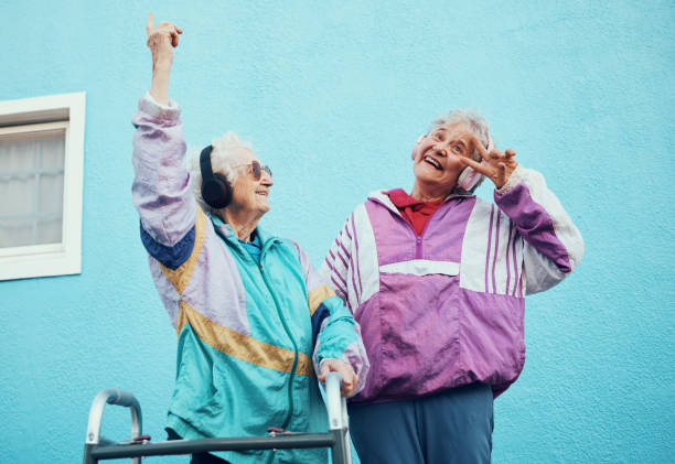 senior, musique et handicap avec une femme amis en plein air dans une ville s’amusant ensemble avec un geste de la main signe de paix. liberté, retraite et heureux avec une femme mature et un ami qui se lient à l’extérieur - female likeness audio photos et images de collection