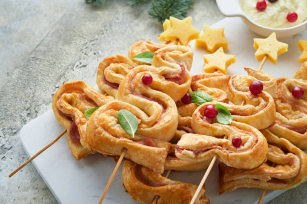 istock Christmas or New Year appetizer. Christmas tree shape puff pastry buns with cheese and ham. Group of Christmas tree shapes on marble stand. Festive idea for Christmas or New Year dinner. Top view. 1459333311