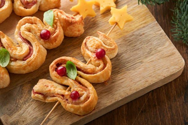 istock Christmas or New Year appetizer. Christmas tree shape puff pastry buns with cheese and ham. Group of Christmas tree shapes on wooden board. Festive idea for Christmas or New Year dinner. Top view. 1459333323