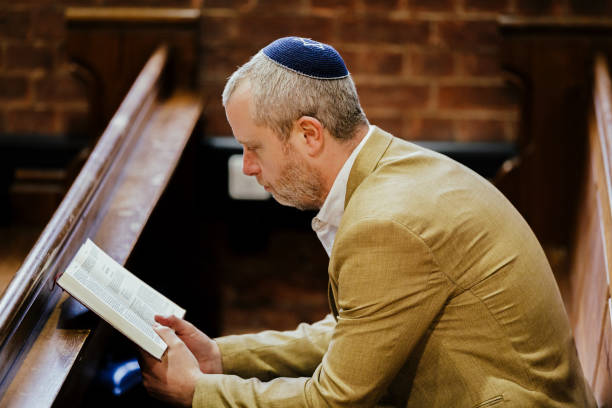 istock Jewish man wearing yarmulke while reading holy book in synagogue 1459334342