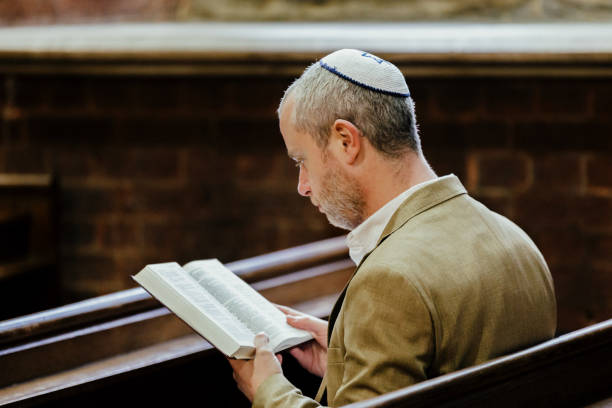 istock Jewish man wearing yarmulke while reading holy book in synagogue 1459334357
