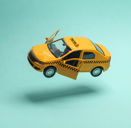 Miniature taxi car levitating on a blue background with a shadow