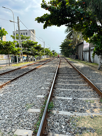 Stock photo showing close-up view of metal railway the line and gravel of southern line diesel railroad track in Colombo, Sri Lanka running parallel to the coast with waves breaking on the rocky shore.