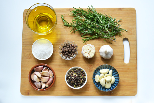 Ingredients for cooking, meat. Rosemary, garlic, pepper, salt olive oil on a wooden board