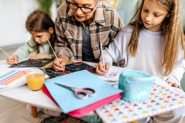 mujer mayor enseñando a sus nietos - diferencia entre generaciones fotografías e imágenes de stock