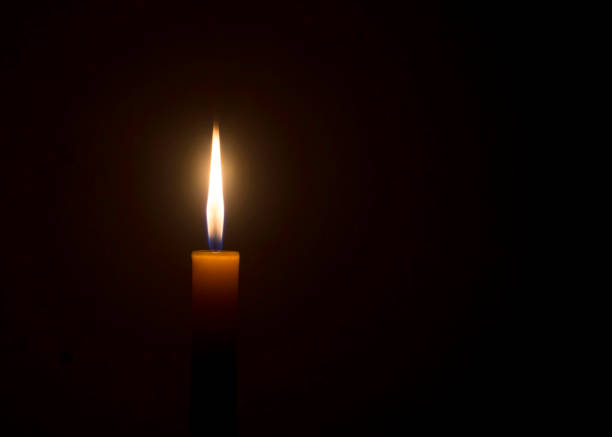 istock Single burning candle flame or light glowing on an orange candle 1459341896