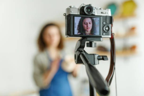 istock Females potter making a vlog, recording online course, lessons in her studion with earthenware shelf on background 1459343561