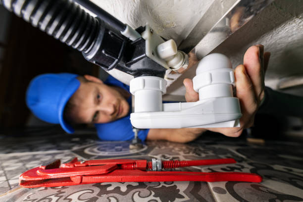 plumbing service. plumber at work in bathroom. repair and install drain siphon under the bath stock photo