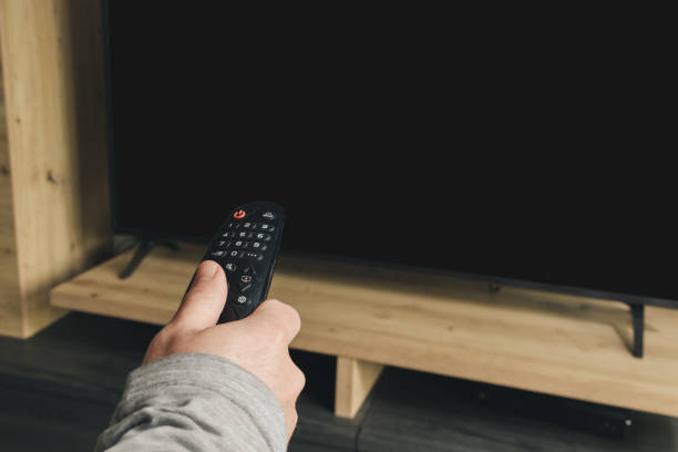 istock hand holding remote tv to interact with tv. copyspace 1459345553