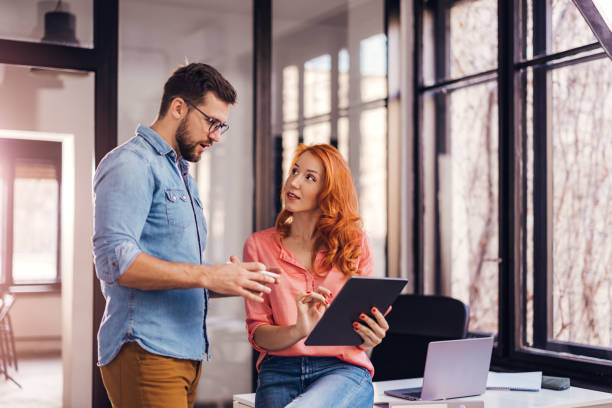 istock young successful people sharing ideas on tablet in modern office. 1459345580