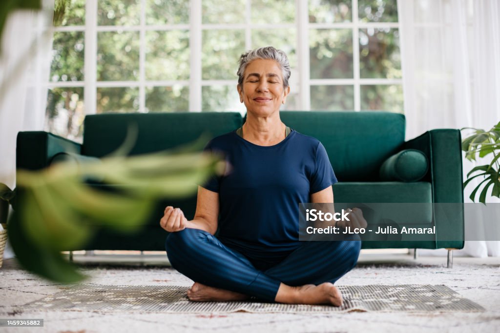 Mit Yoga den Geist entspannen und innere Ruhe finden: Seniorin meditiert zu Hause - Lizenzfrei Meditieren Stock-Foto