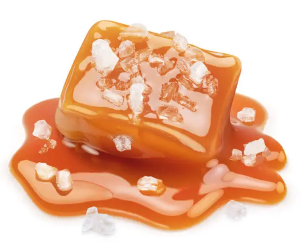 Photo of Salty caramel candy in milk caramel sauce with salt crystals isolated on white background.