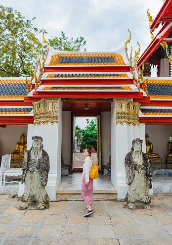 Young Caucasian woman in white dress  exploring  Wat Pho in Bangkok