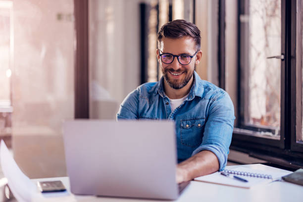 istock Smiling businessman sitting in office and working on laptop. 1459347382