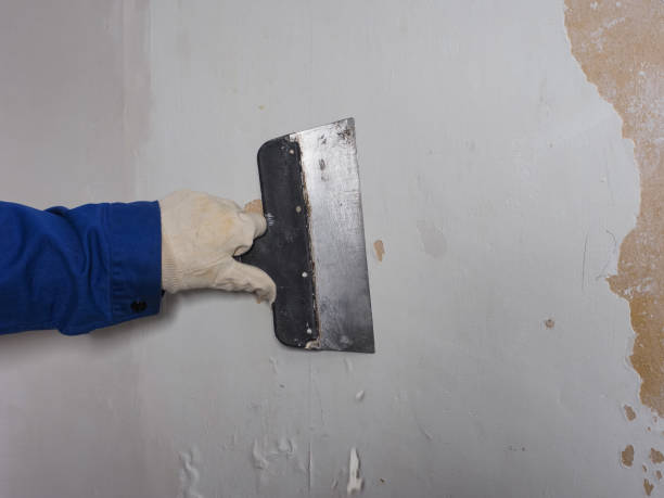 istock a worker's hand in a glove with a spatula removes old plaster from the wall 1459349827