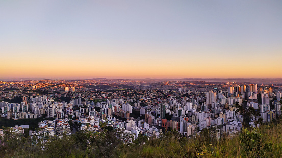 Dawn with sunrise in the city of Belo Horizonte, in the state of Minas Gerais, seen from the top of a mountain that is within the city. This mountain range is in the extreme west and allows a wide view of the entire metropolitan region. The morning lights leave the city and the camos on top of the mountain are a very strong yellow.