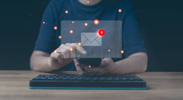 le mani dell'uomo d'affari utilizzano la digitazione mobile sullo schermo e la navigazione in internet sul tavolo dell'ufficio con l'icona dell'e-mail, il concetto di email marketing, l'invio di e-mail o la lettera di notizie, la rete internet di lavoro on - cassetta postale per linvio della posta foto e immagini stock