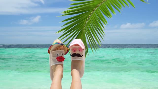 Hotel white slippers are decorated to match the cheerful faces of newlyweds having a rest. The concept of summer vacation and honeymoon in hot exotic countries.